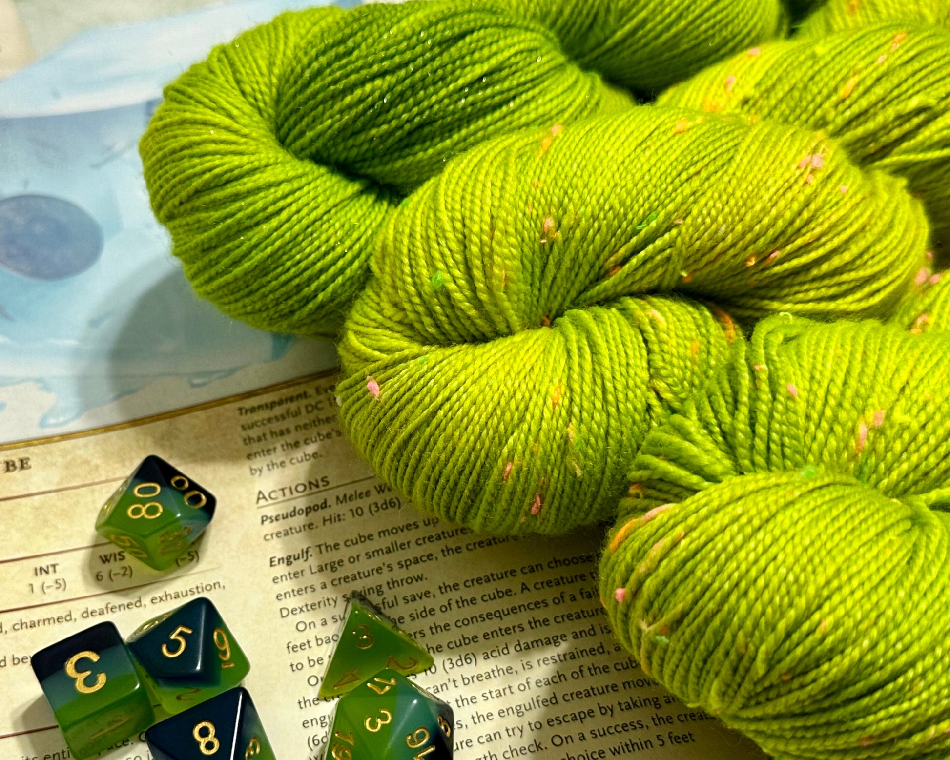 Green yarn skein with green dice on a book