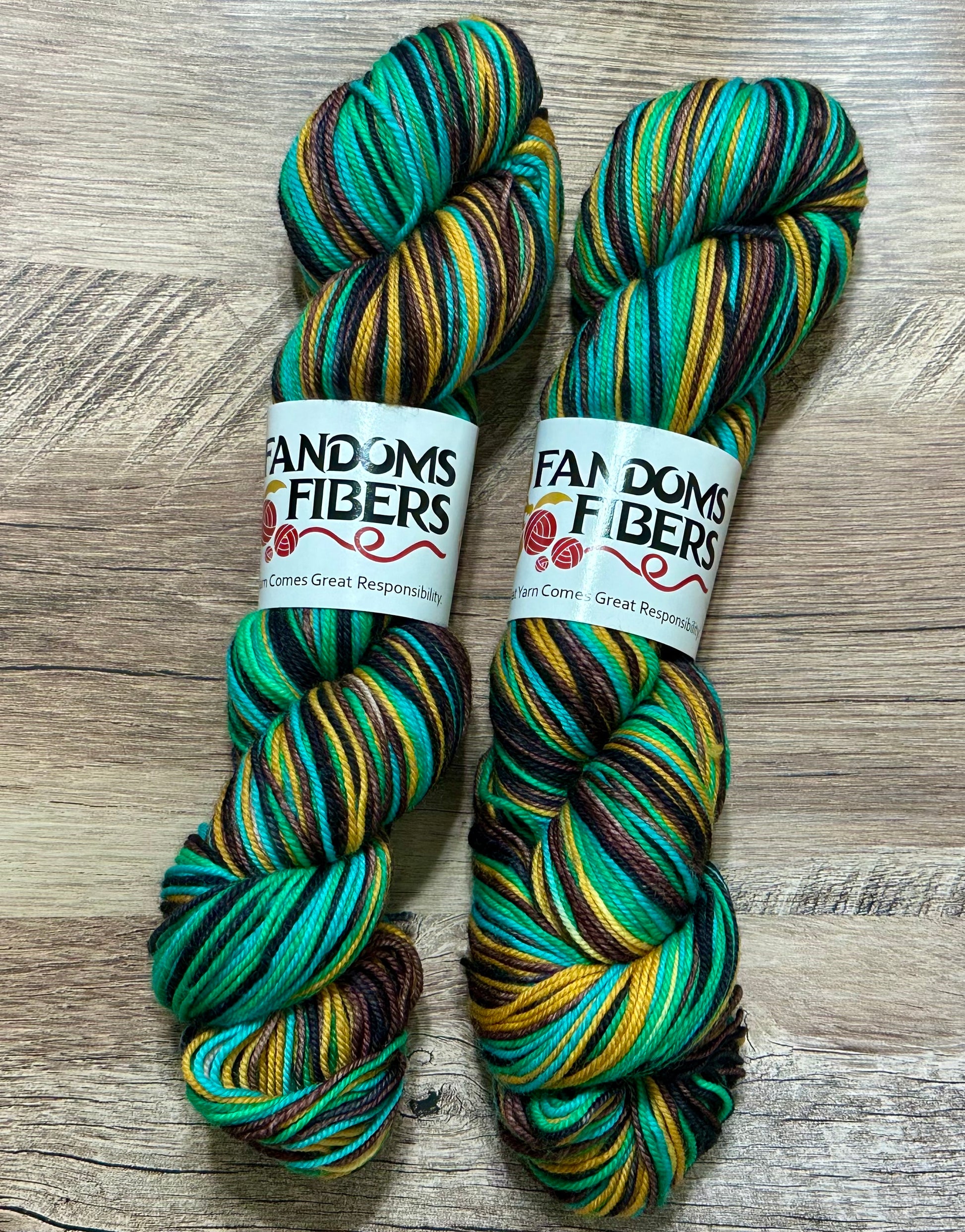 Two skeins of self-striping multicolored yarn with labels from 'Fandoms & Fibers'.